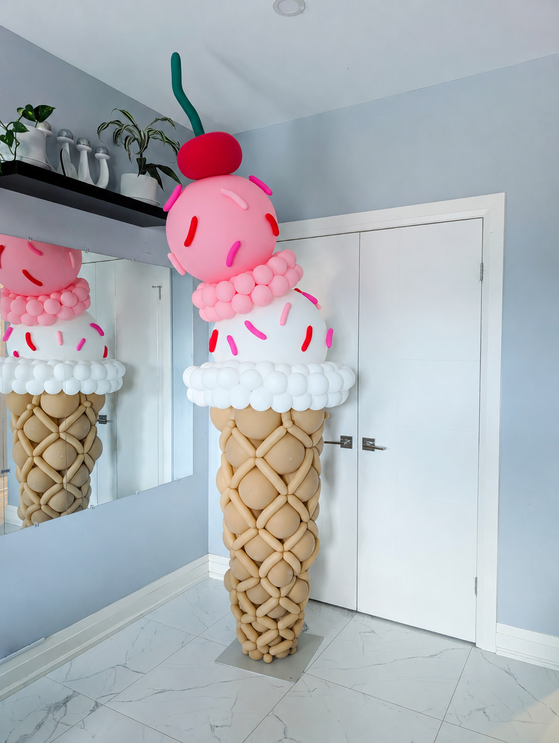 Giant balloon ice cream cone sculpture with two scoops, colourful sprinkles and a cherry topper.