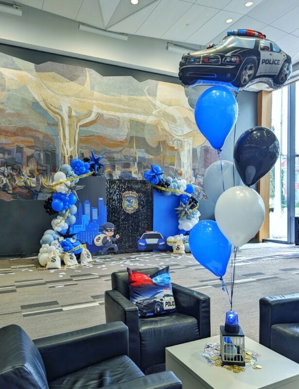 Blue, black and silver helium balloon bouquet topped with a police car balloon.