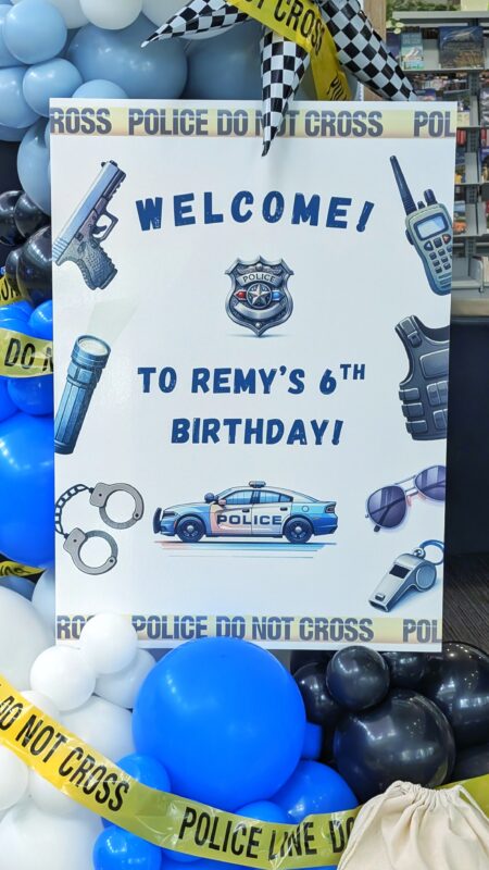 Close view of Remy’s police-themed birthday welcome sign with balloons and caution tape.