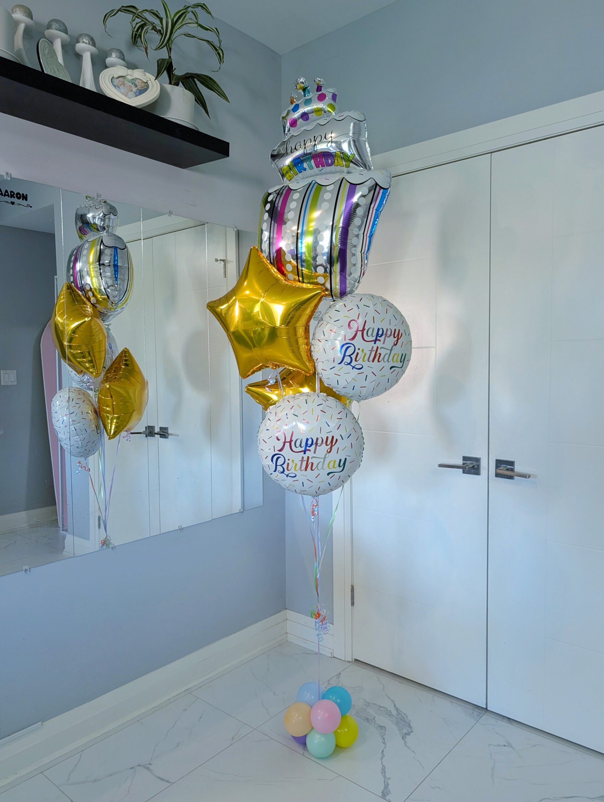 Birthday balloon bouquet with a colourful cake balloon, sprinkle birthday foils, and metallic gold stars.