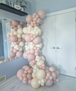 Blush pink and ivory organic balloon garland arranged around a wall mirror with assorted balloon sizes.