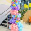 Pastel balloon column with pink, purple and blue balloons, striped candy canes and colourful bow accents.