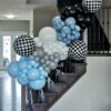 Black, blue, grey and white balloon garland with oversized black-and-white checkered balloon accents.