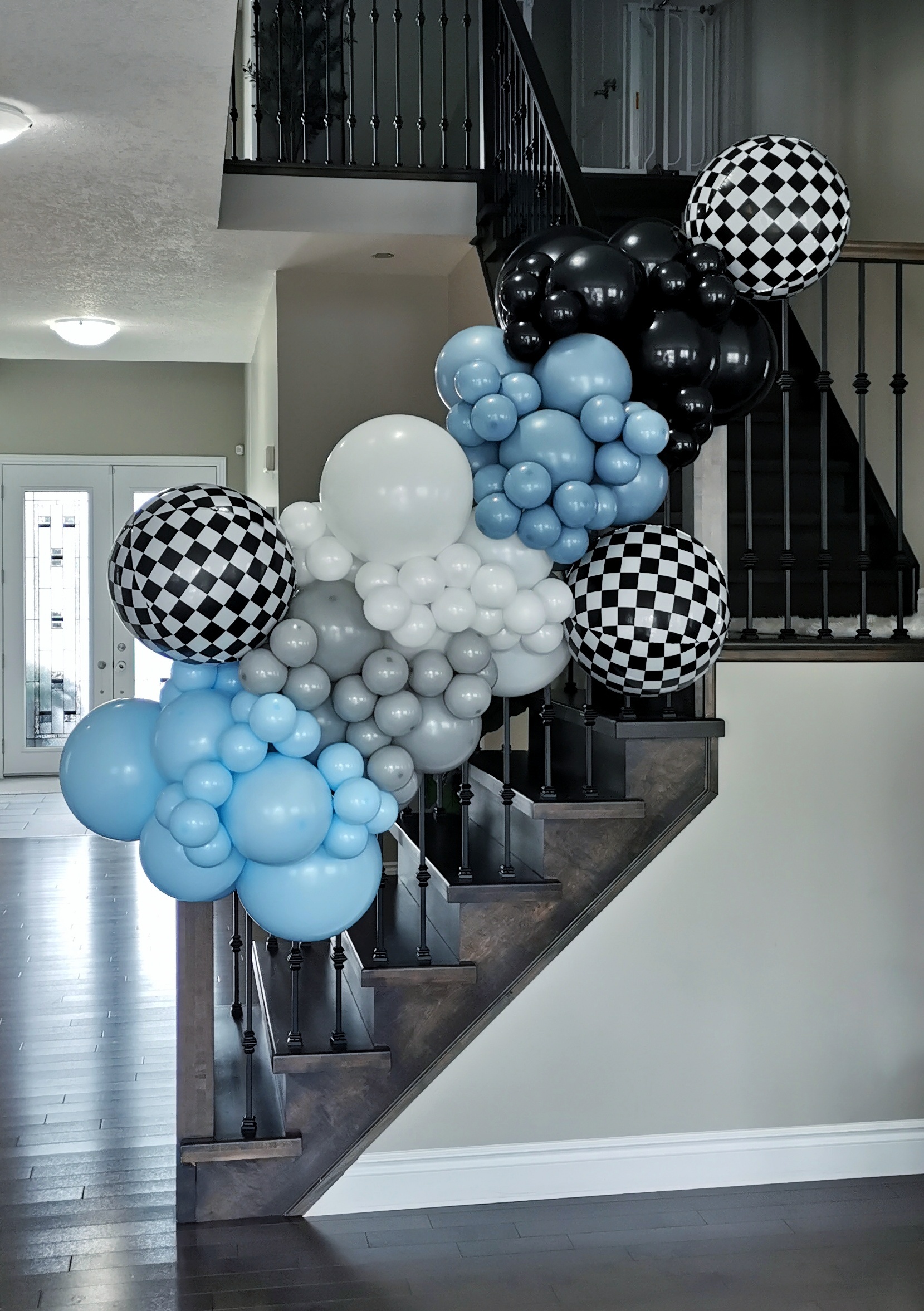 Black, blue, grey and white balloon garland with oversized black-and-white checkered balloon accents.
