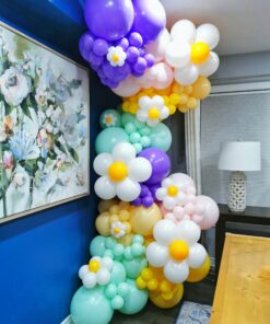 Pastel balloon garland with white daisies and purple, mint, blush and yellow balloons in a floor-to-ceiling display.