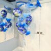 Blue shark birthday balloon bouquet with a giant shark foil and feather-filled clear balloons.