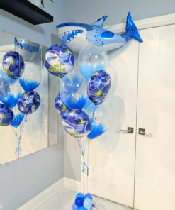 Blue shark birthday balloon bouquet with a giant shark foil and feather-filled clear balloons.