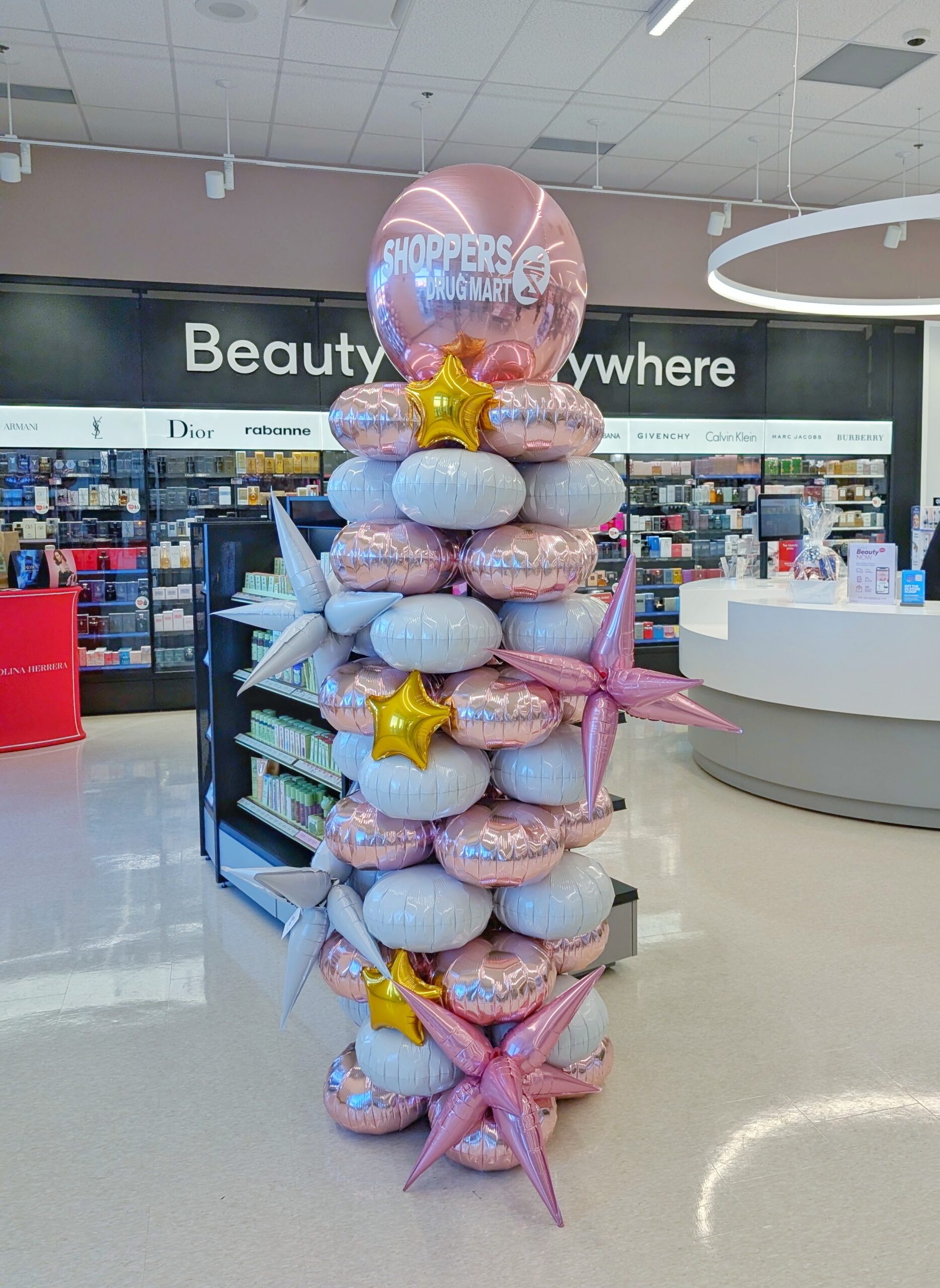 Latex-free rose gold and silver foil balloon column with metallic starbursts, gold stars and a branded topper.