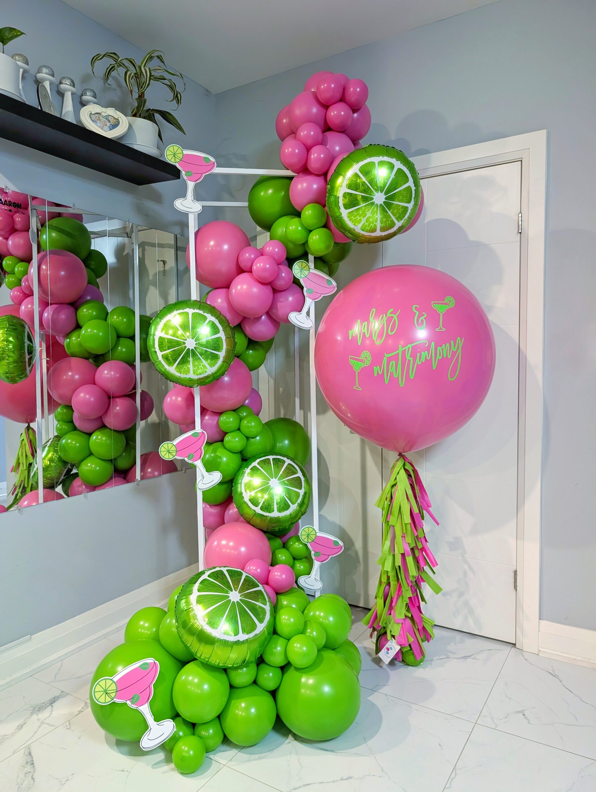 Pink and green margarita balloon garland with lime accents and a personalized jumbo helium balloon.