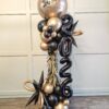 Black and gold New Year balloon column with 2026 numerals, starbursts, fringe and a custom branded topper.