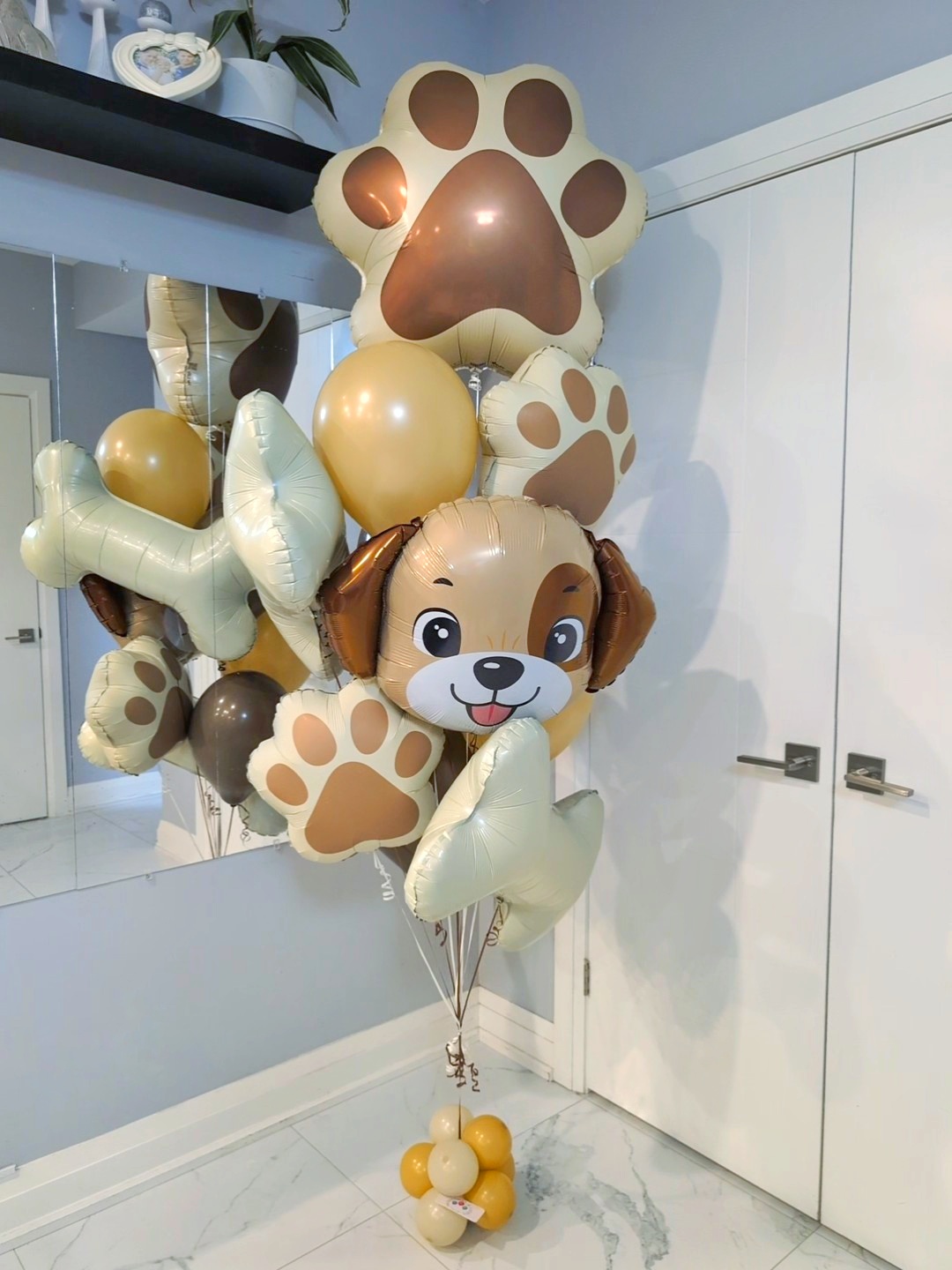 Puppy birthday balloon bouquet with paw prints, bones, and cream, gold, and brown balloons.