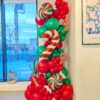Red and green Christmas balloon column with oversized peppermint candies and striped candy cane balloons.