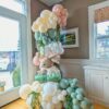 Pastel bunny balloon column with blush, sage, ivory and white balloons, foil rabbits and cascading greenery.