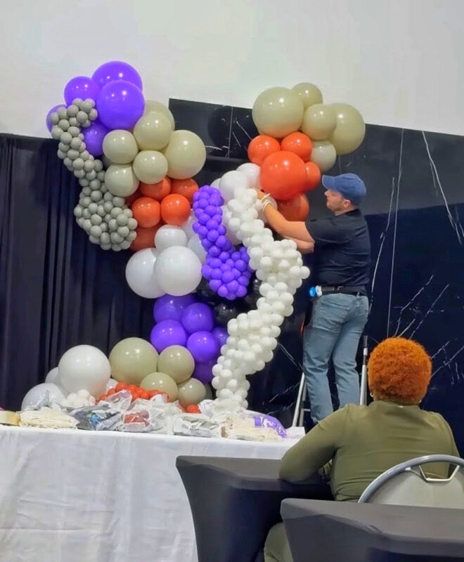 Instructor attaching a white five-inch caviar garland to the balloon installation.