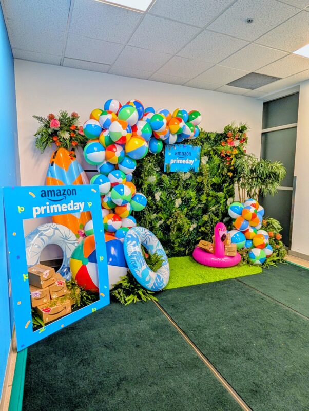 Tropical greenery backdrop with beach balls, inflatables, and Amazon Prime Day signage in Kitchener.