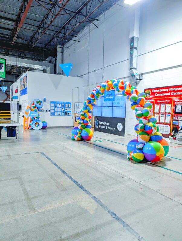 Large Beach ball arch with branded signage in Amazon warehouse.