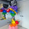 Rainbow Back-to-School balloon column with apples, starbursts, tassels and a personalized pencil.