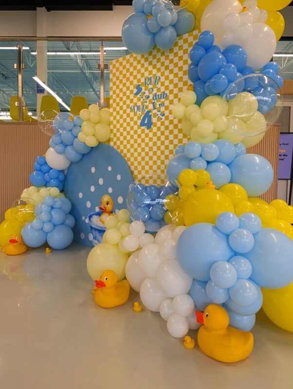 Bubble-inspired clear balloons and rubber duck accents surrounding the birthday backdrop.