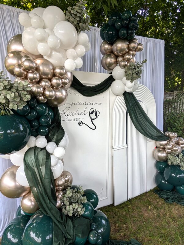 Deep green, champagne and white balloons framing a custom respiratory therapy backdrop.