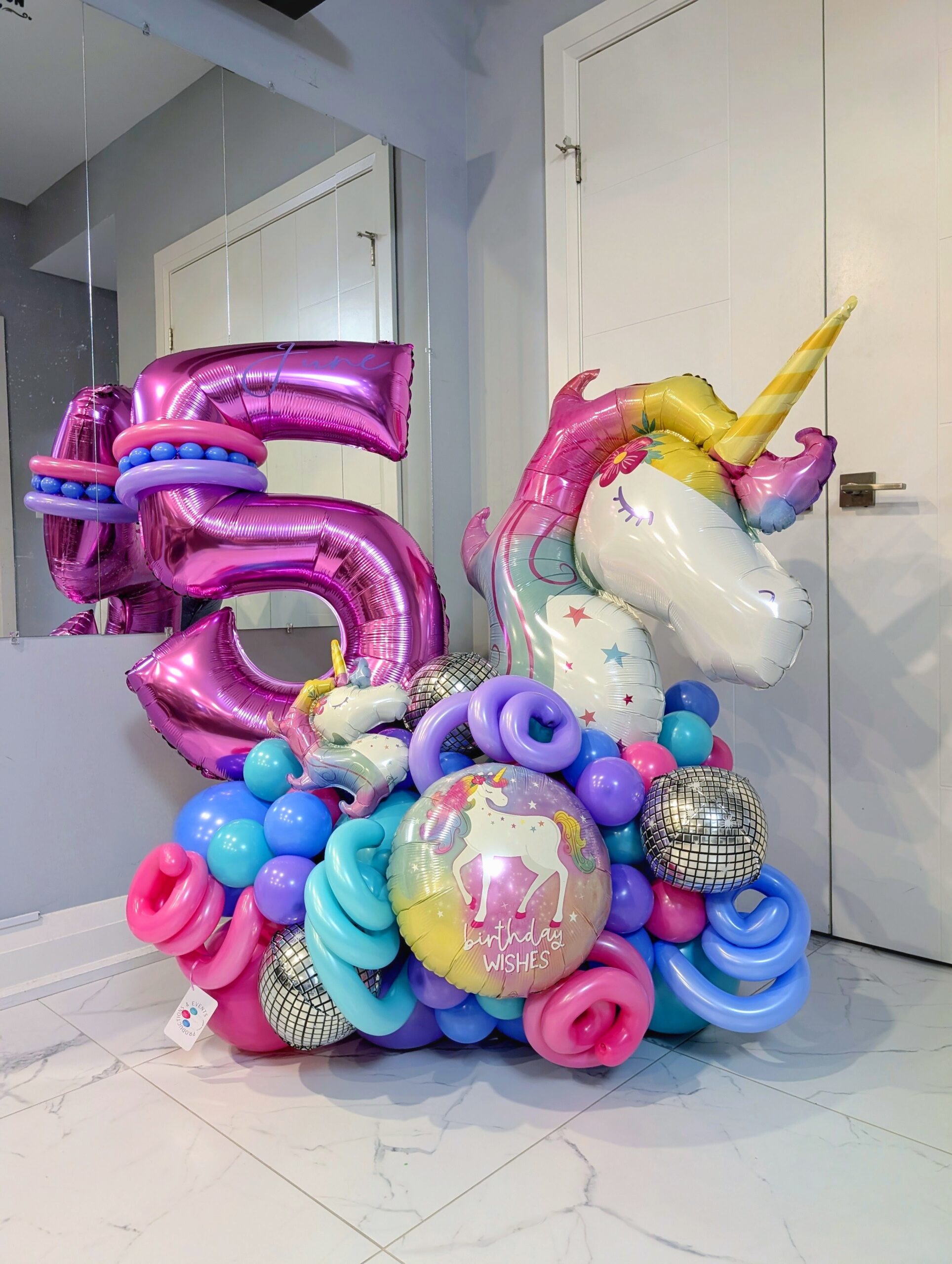 Colourful unicorn birthday number stack with disco ball balloons, twisted accents, and a personalized name decal.