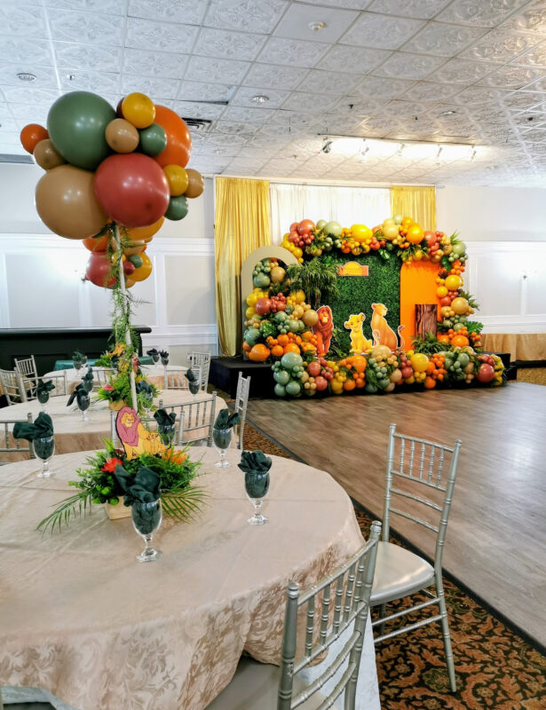 Tall earthy balloon centrepiece with trailing greenery above a safari baby shower table