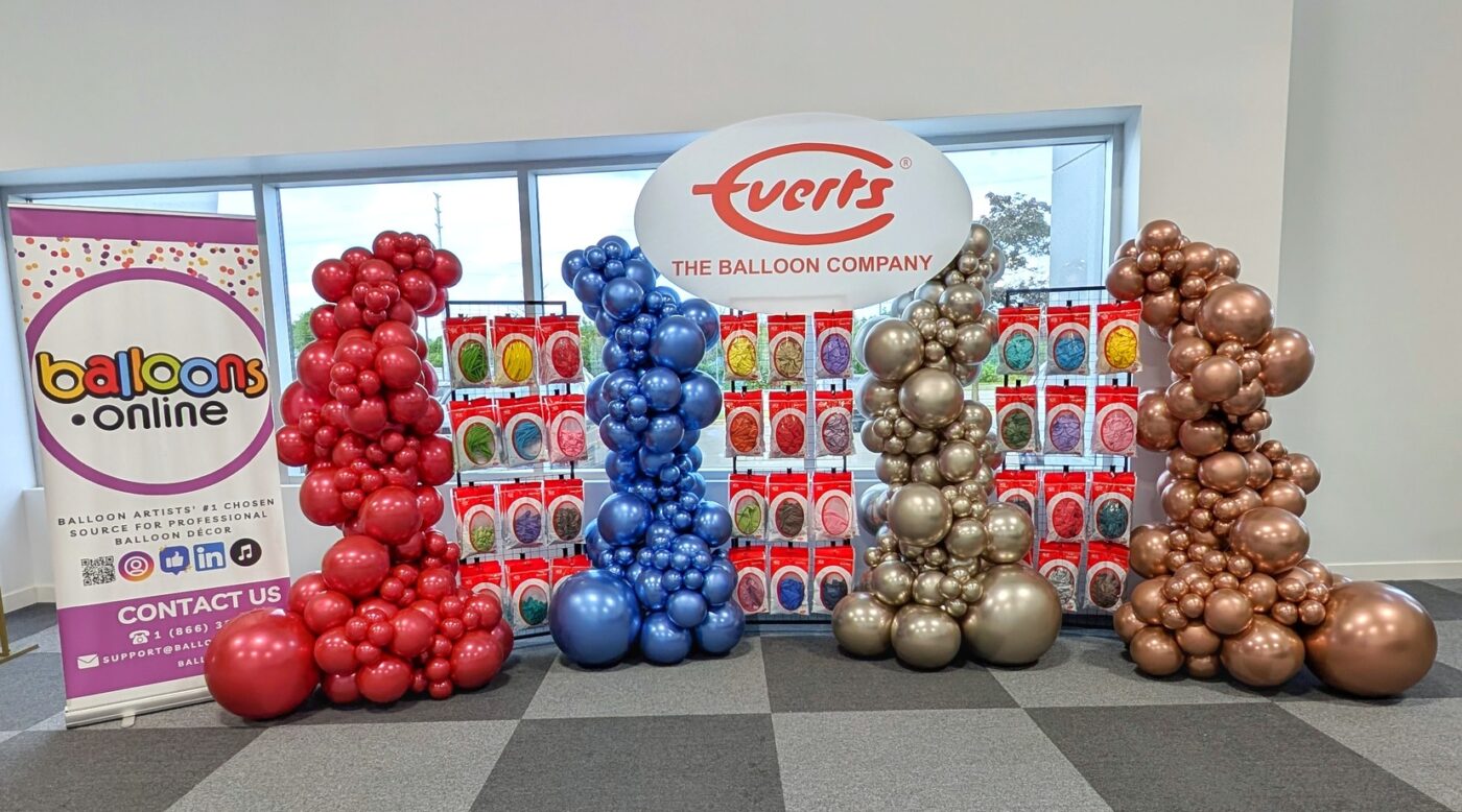 Everts Balloon Company launch display with four Luxe balloon columns and product racks.