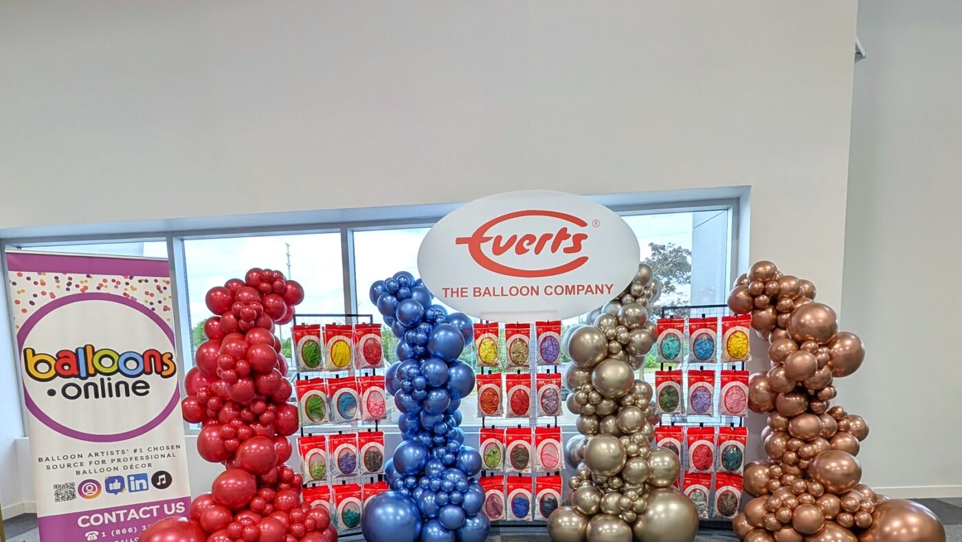 Everts Balloon Company launch display with four Luxe balloon columns and product racks.