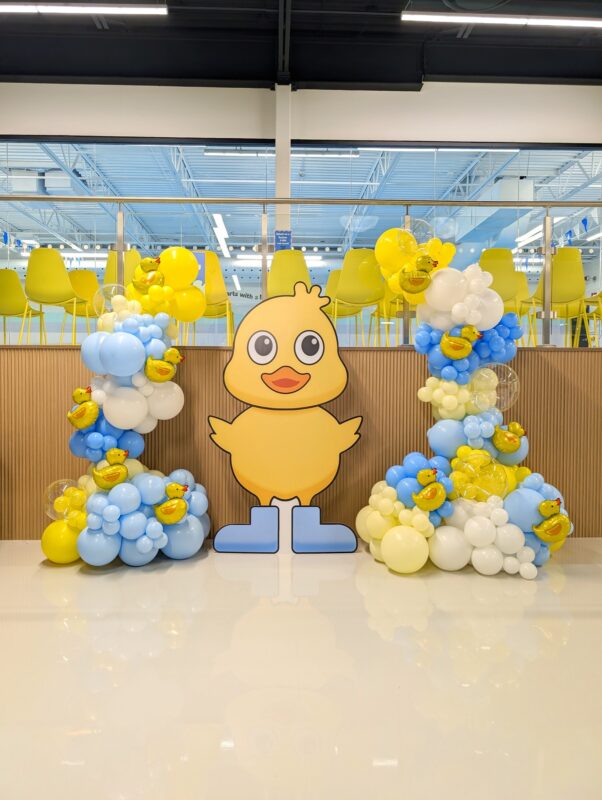 Large custom duck cutout between blue, yellow and white balloon displays with duck accents.