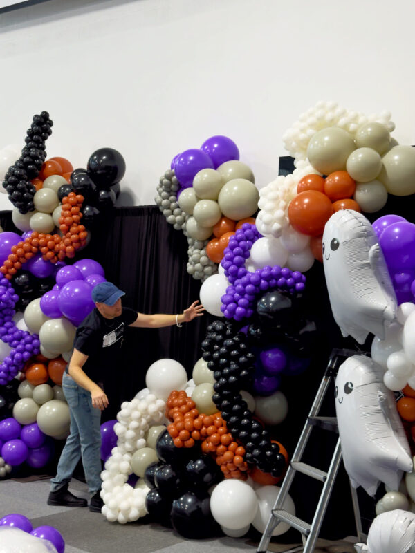 Instructor presenting a layered Halloween balloon garland with foil ghosts and caviar balloon details