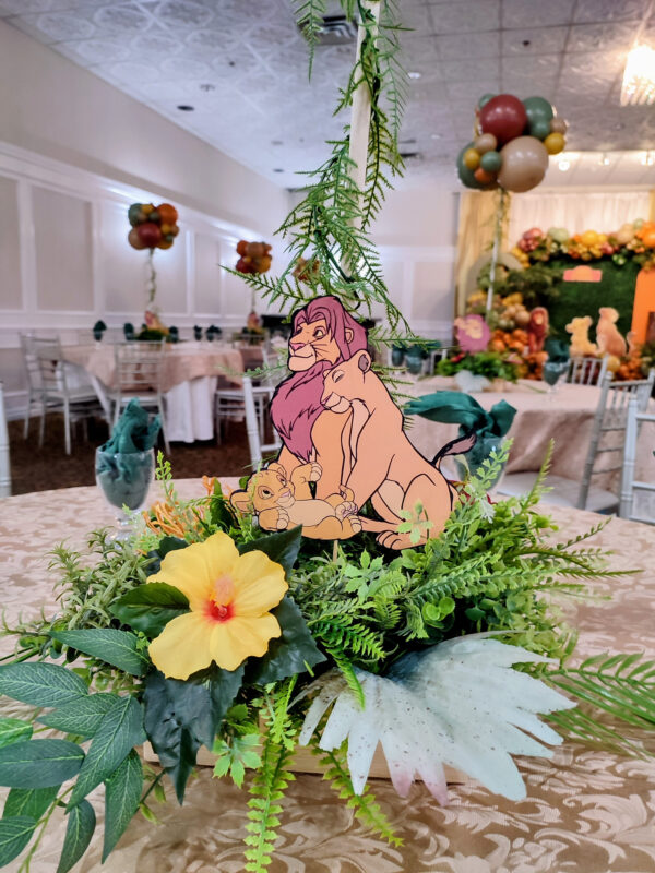Lion King floral centrepiece with tropical greenery, bright flowers and a Simba cutout