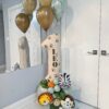 Safari birthday number stack with jungle animals, tropical leaves, sage balloons, paw prints, and a personalized name decal.