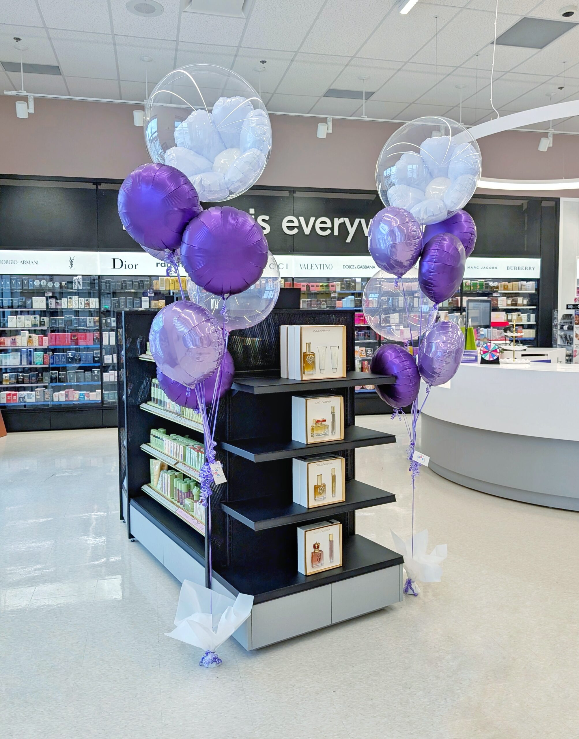 Purple and lavender helium bouquet with a clear bubble balloon containing a large white foil flower.