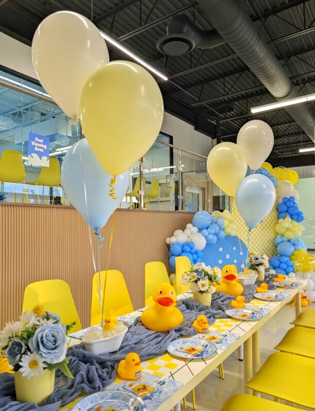 Rubber duck birthday table styling with soft balloon bouquets and a custom backdrop behind it.