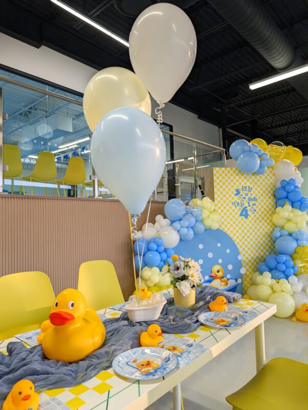 Kids table with faux florals, rubber ducks, themed tableware and bathtub centrepieces.