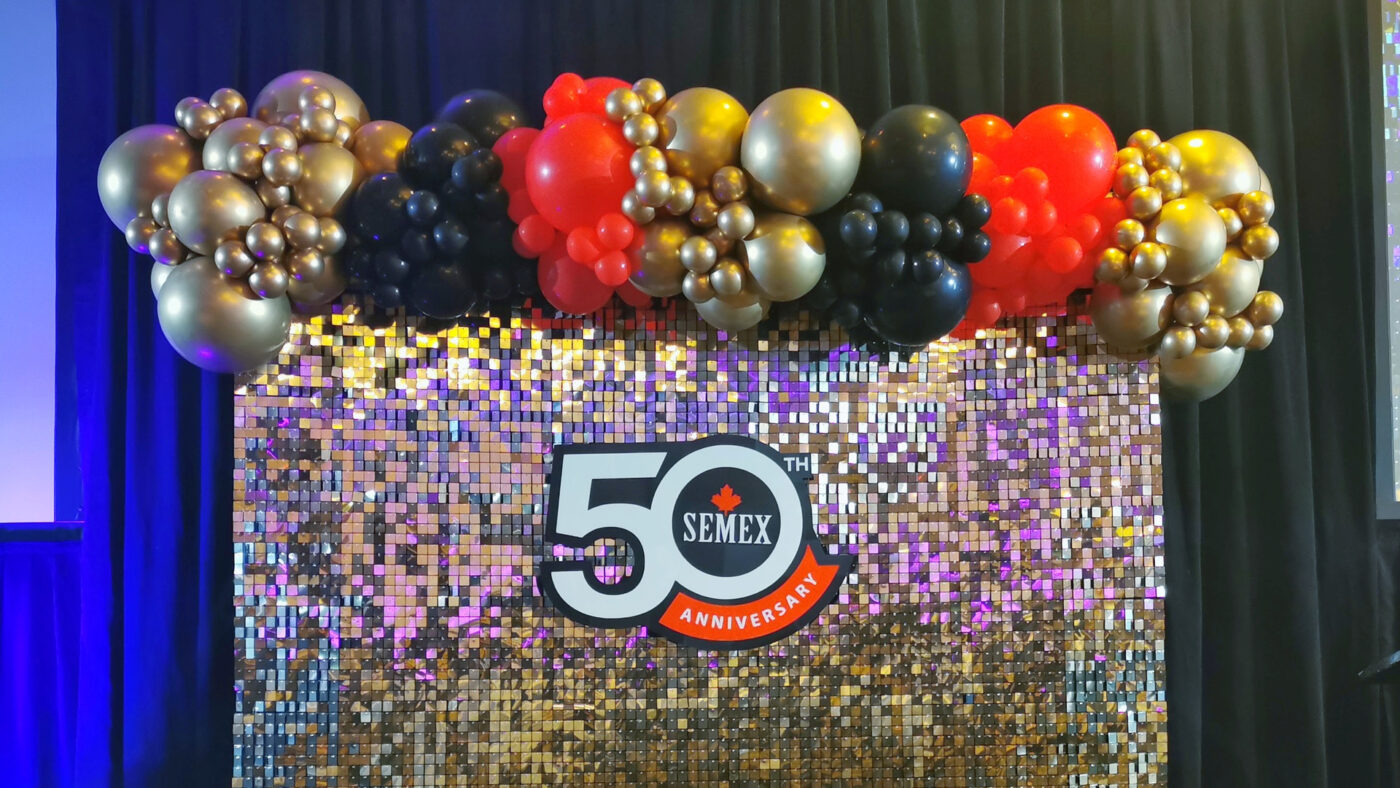 Gold shimmer wall with red, black and gold balloons and Semex 50th anniversary branding in Guelph