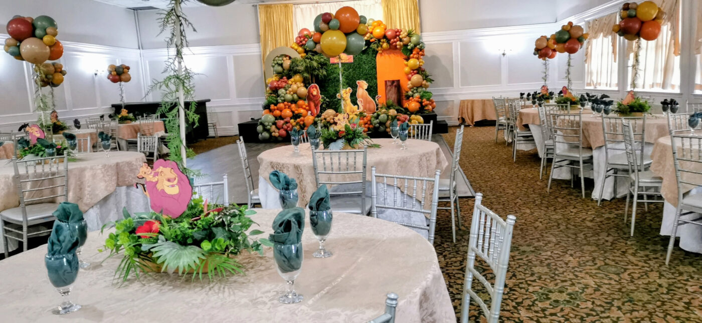 Banquet hall styled for a surprise Lion King baby shower with coordinated tables and balloons